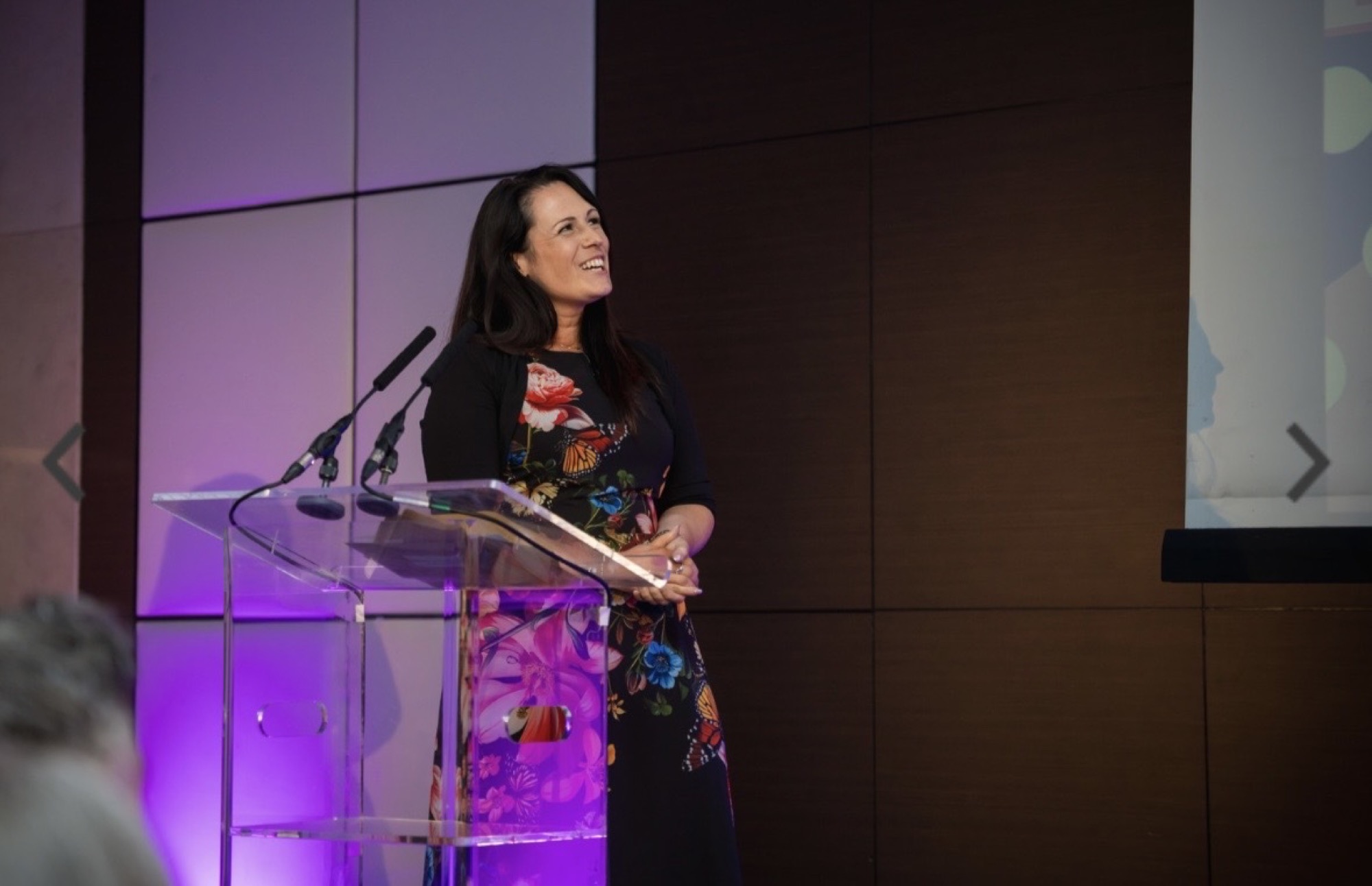 Sadie Restorick on stage at a podium, lit in purple